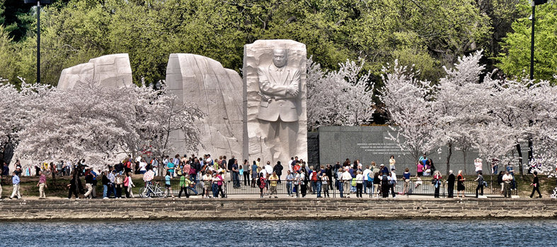 MLK Memorial across tidal basin cherry blossoms with a crowd of people