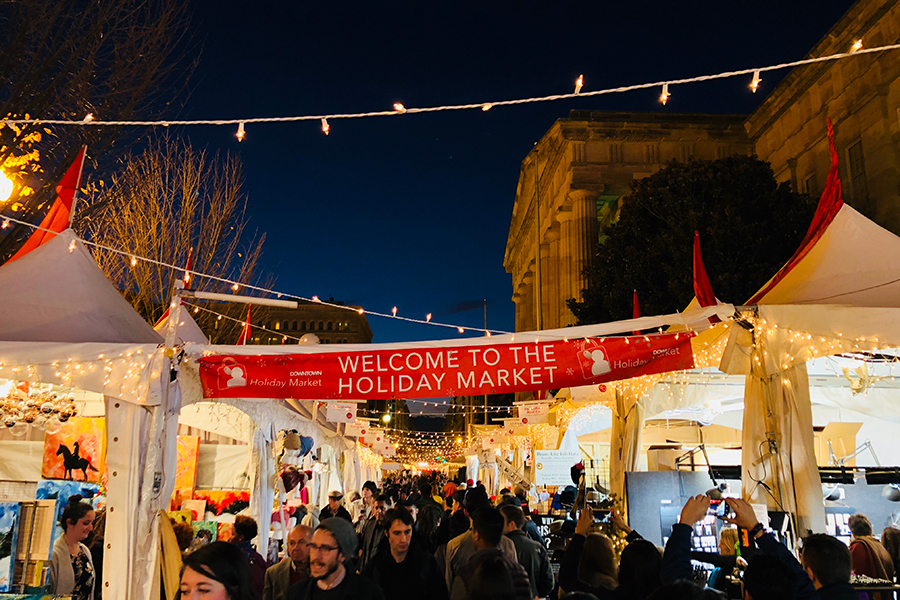 夜間市中心假日市場的照片，市場帳篷上方掛著燈串