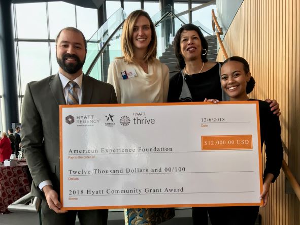 Four people stand with a large check from Hyatt Community Foundations to the American Experience Foundation