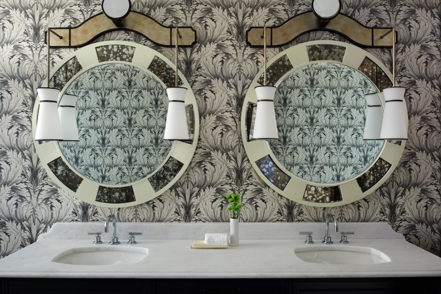 double bathroom vanity with round mirrors, white countertop, and funky wallpaper