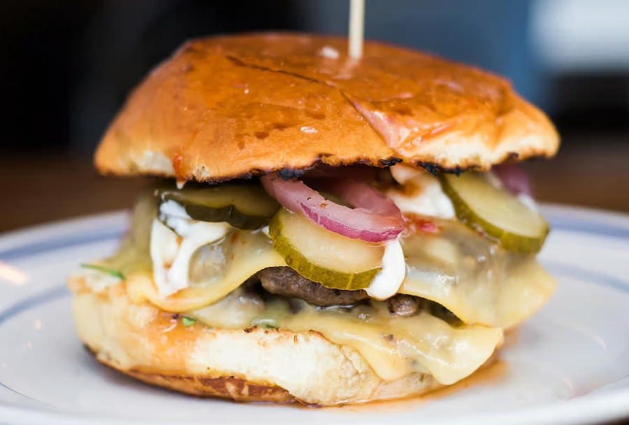 close-up de hambúrguer com picles, cebola e queijo