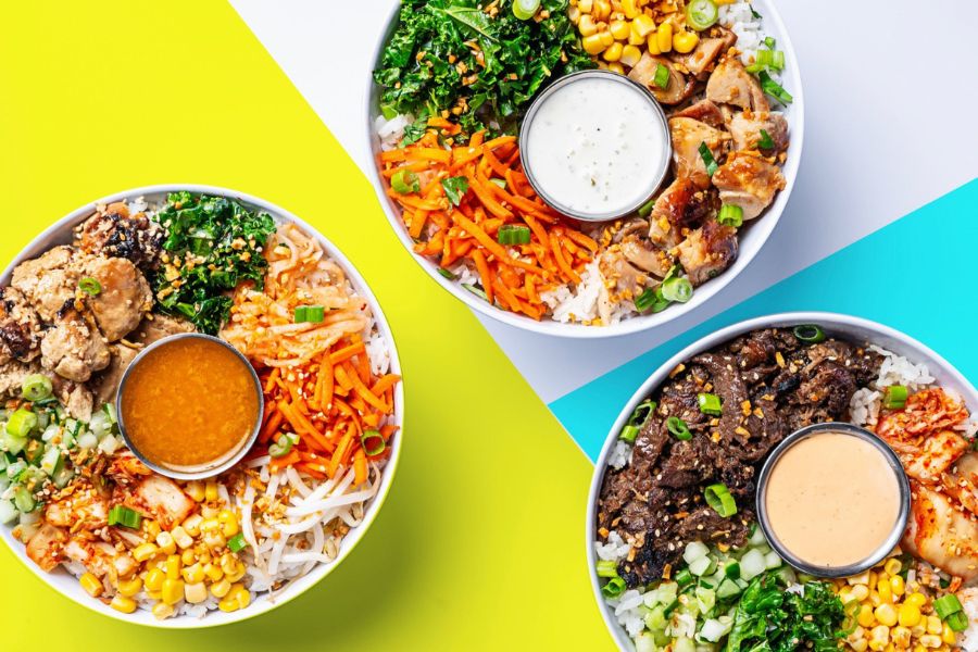 Three colorful bowls filled with vegetables, rice, and proteins, each topped with a different sauce. The bright background adds to the fresh and appealing presentation.
