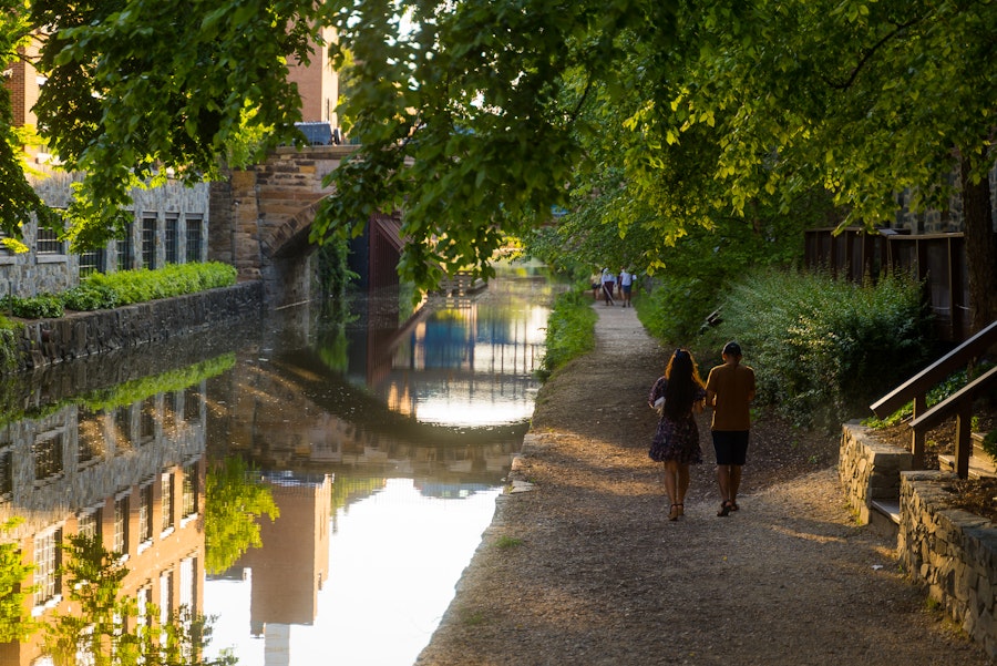 一对夫妇沿着乔治城运河旁的林荫小路散步。