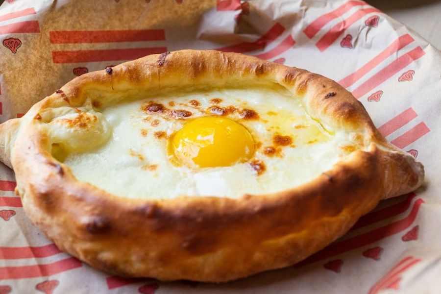 Close-up of Khachapuri at Supra, featuring melty cheese in a bread bowl topped with an egg yolk