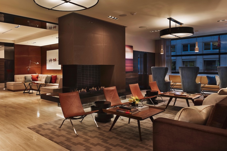 A modern lounge area with a central fireplace, brown leather chairs, and sleek, contemporary decor, creating a cozy and stylish atmosphere.