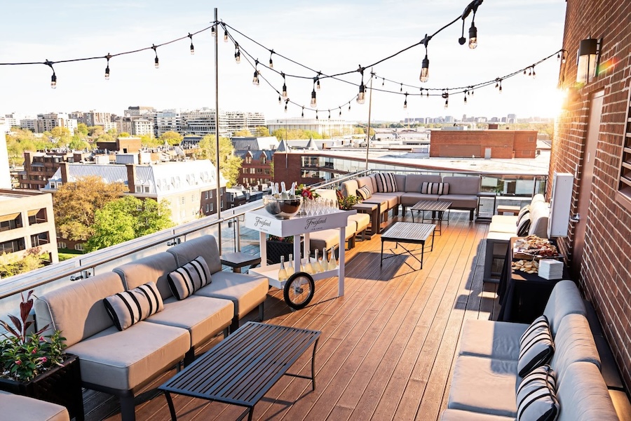 A rooftop lounge with string lights, comfortable seating, and a panoramic view of the city, perfect for enjoying a sunset or hosting an outdoor gathering.