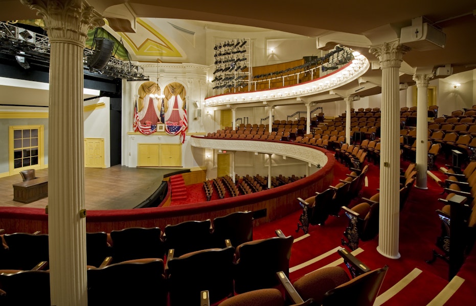 The historic Ford's Theatre features elegant red seating, curved balconies, and a stage framed by rich gold accents.