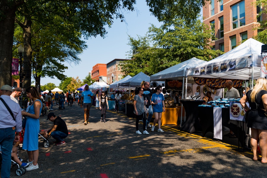 Shaded by trees, visitors browse artisan stalls at the bustling Eastern Market outdoor fair in Washington, D.C.