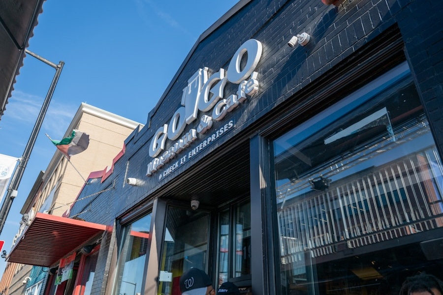 The entrance to the Go-Go Museum & Café features bold signage on a black-painted brick building under a bright blue sky.