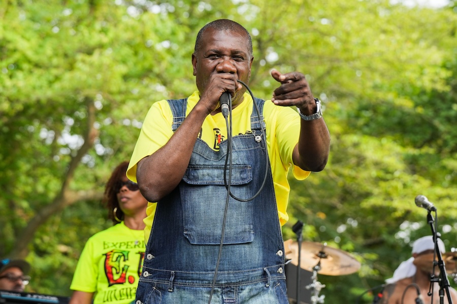 A singer in denim overalls passionately performs on stage at the Home Rule Music Festival.