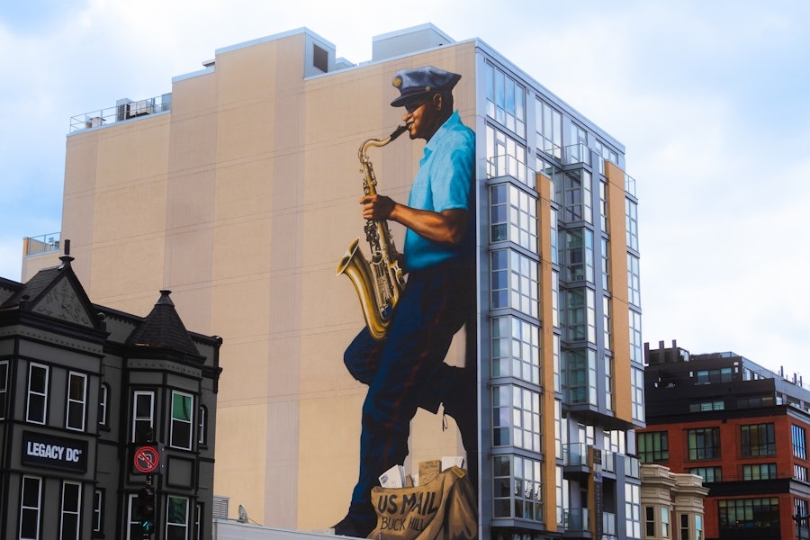 A mural on a building in Washington, DC, depicts a mailman playing the saxophone, honoring jazz musician Buck Hill.