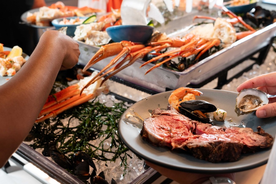 A seafood buffet with crab legs, oysters, shrimp and prime rib on ice.