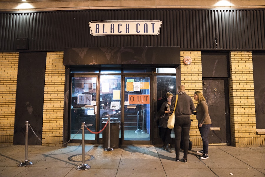 Menschen stehen unter stimmungsvoller Beleuchtung vor dem Nachtclub Black Cat in der 14th Street und warten darauf, den Veranstaltungsort zu betreten.