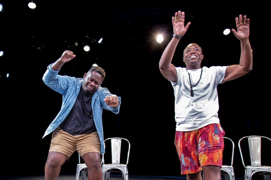 Zwei Darsteller spielen unter hellem Licht des Washington Improv Theaters lebhaft eine komische Szene auf der Bühne.