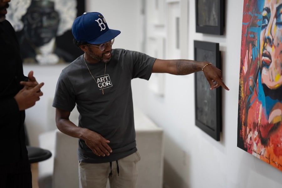 A visitor points to a colorful contemporary painting while viewing artwork inside a gallery in Washington, DC.