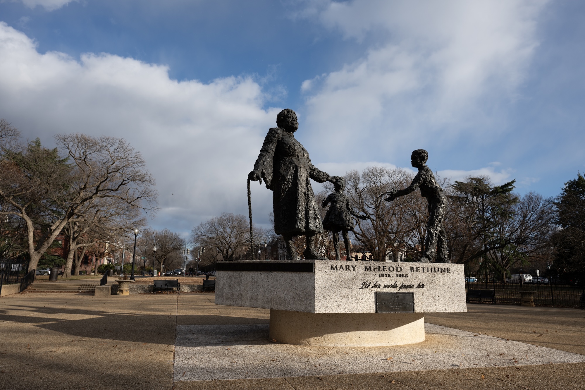 The Mary McLeod Bethune statue stands in Lincoln Park in Washington, DC, depicting the educator and civil rights leader with two children under a partly cloudy sky.