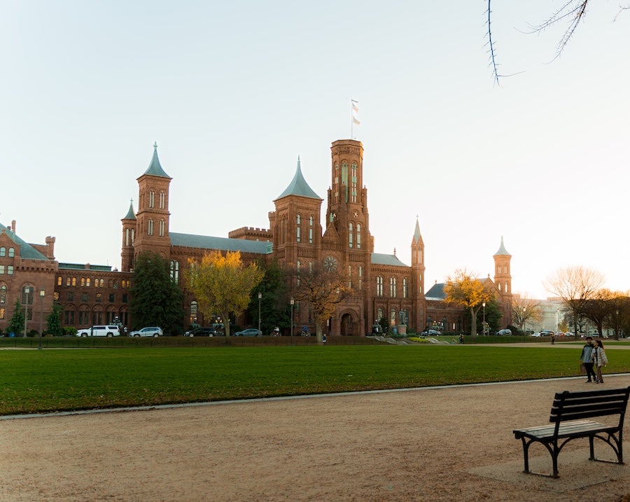 A view of the Smithsonian Castle across the National Mall in golden, summer light.