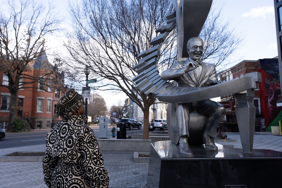 A visitor looks up at the Duke Ellington statue along a neighborhood street in Washington, DC.