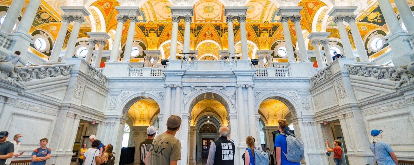 Visitors look up at the ornate columns and golden ceiling inside the Library of Congress Great Hall.