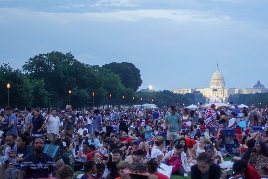 Large crowd on the National Mall with the Capitol dome in the distance at dusk.