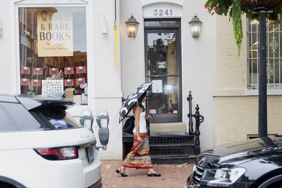 Storefront entrance with scooters parked outside, cars along the street