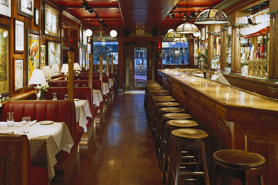 Cozy empty restaurant with checkered tablecloths and a long wooden bar with stools