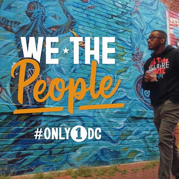 Chef Anthony Jones standing by mural, alongside “We The People” graphic
