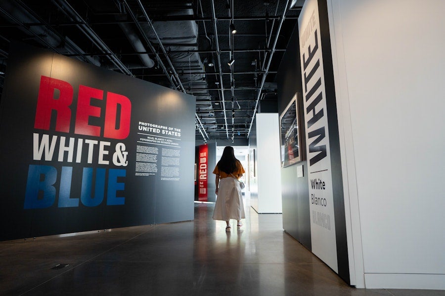 Museum hallway with large “RED WHITE & BLUE” wall graphic and visitors walking