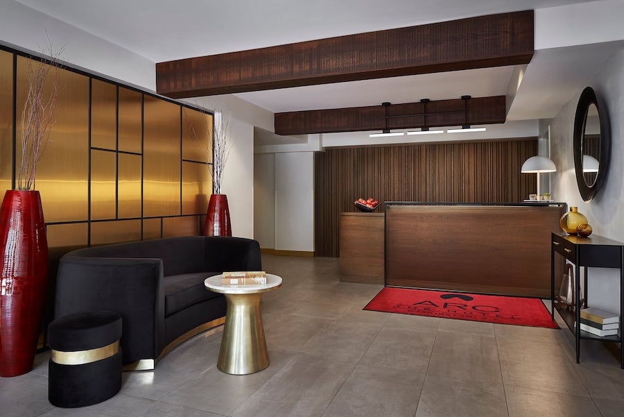 ARC Hotel Washington DC Series by Marriott hotel lobby with dark wood reception desk and red rug, black chairs, and vases