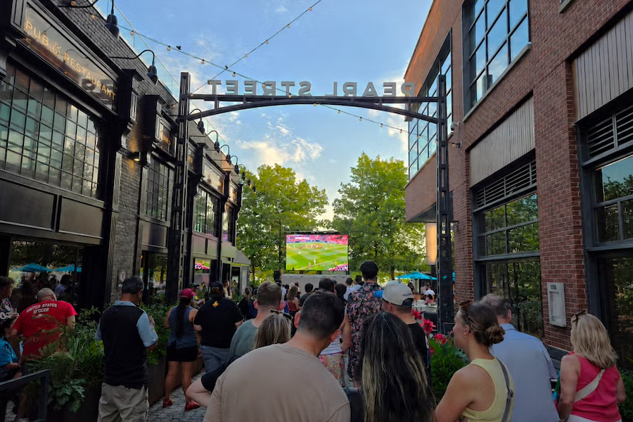 Crowd watching soccer on a screen on a closed-off city street