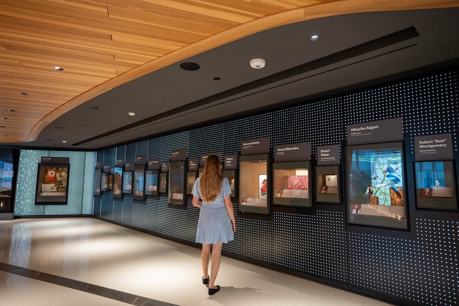 Woman in blue dress walking past framed posters in a modern gallery corridor
