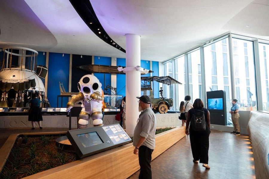 Visitors viewing exhibits in a modern museum with a large astronaut display