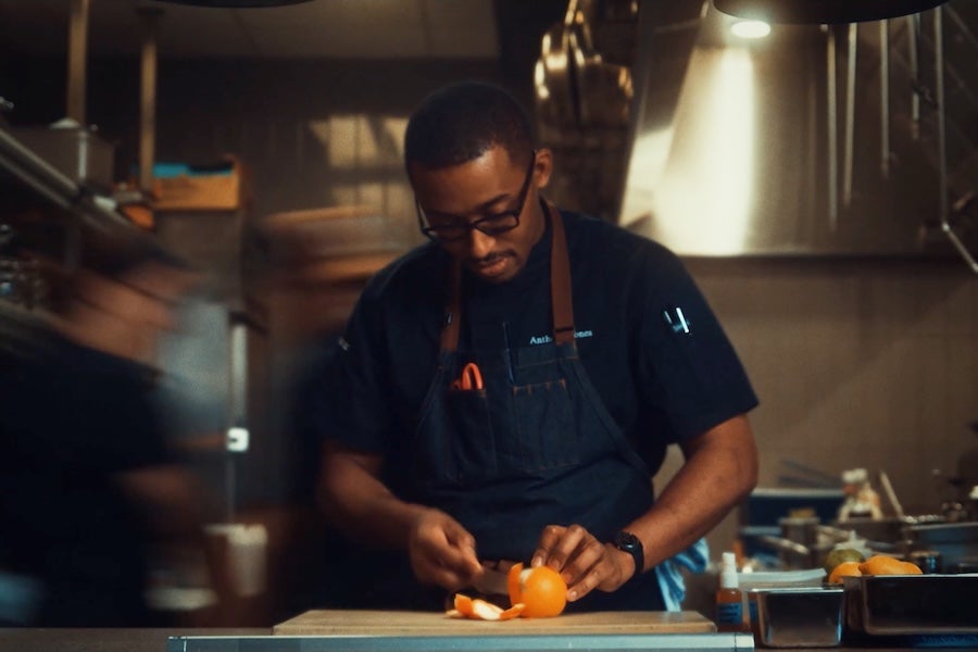 Chef in a dim kitchen preparing food under warm task lighting