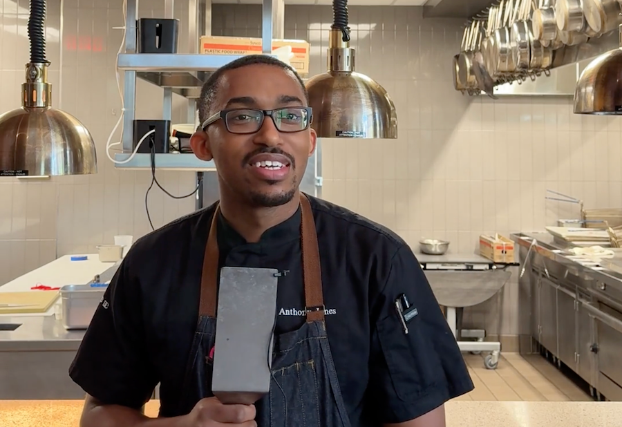 Chef in an apron holding a microphone in a restaurant kitchen