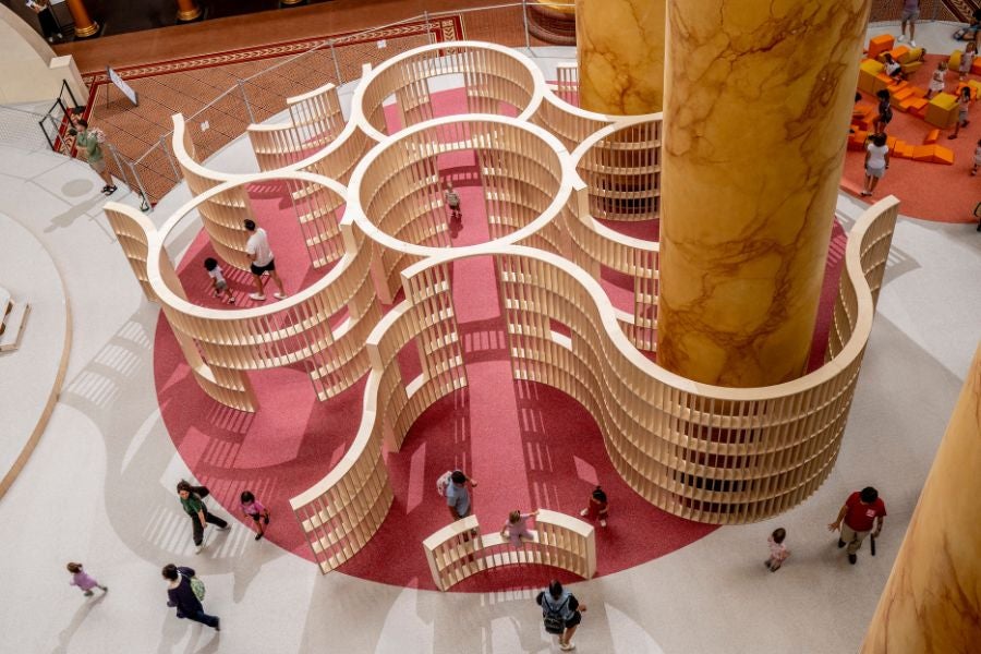 Visitors exploring a circular wooden maze in the National Building Museum’s PLAYGROUND exhibition.