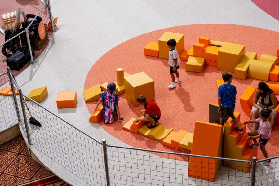 Children building and playing with oversized foam blocks in an interactive play area at the National Building Museum’s PLAYGROUND exhibition.