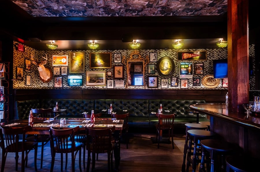 Dimly lit bar with framed wall art and tables and chairs