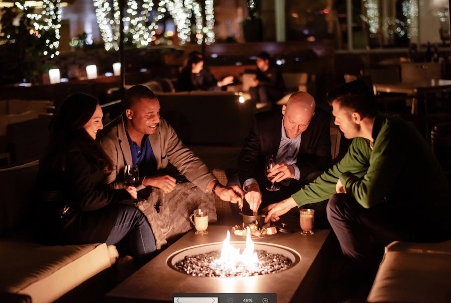 People sitting around a glowing fire pit at night at Blue Duck Tavern
