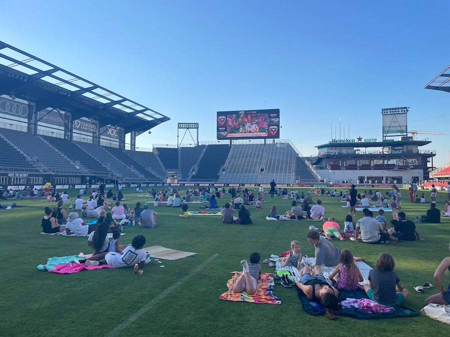 People lounging on a stadium field on blankets in sunny weather