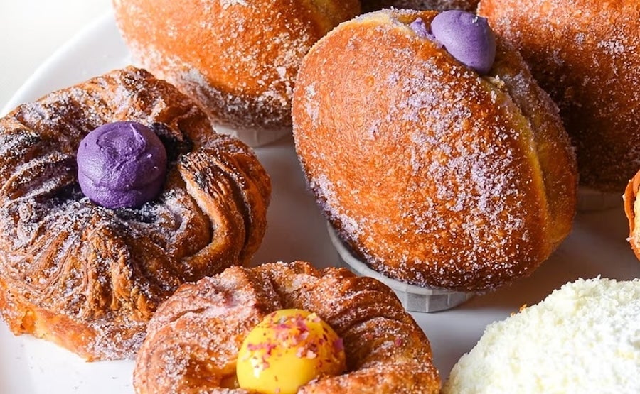 Assorted pastries dusted with powdered sugar on a plate, including croissants and filled doughnuts