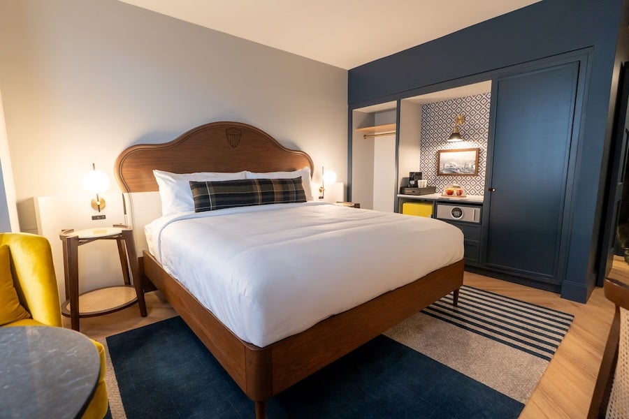 The Hoya Hotel modern hotel bedroom with large bed, dark blue wall and warm lighting