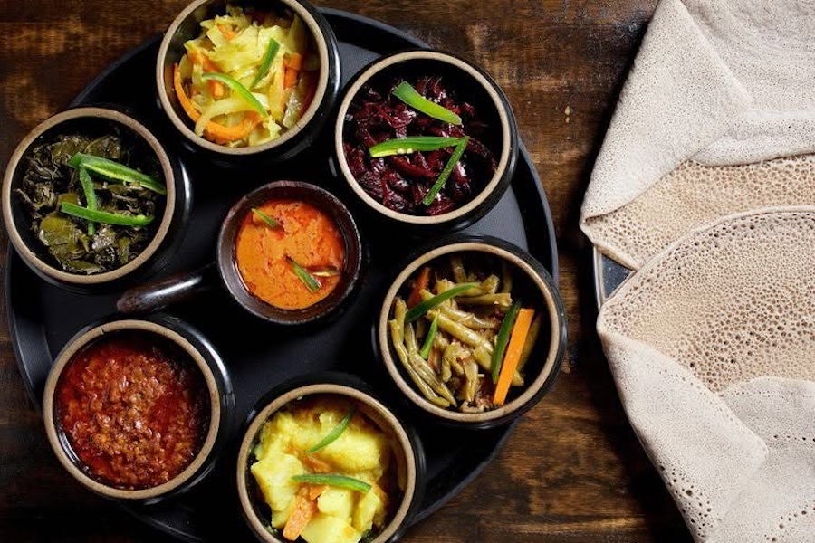 Assorted Ethiopian dishes in black bowls on a wooden table 