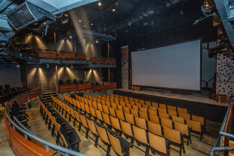 Empty Woolly Mammoth theater with yellow seats facing a large screen