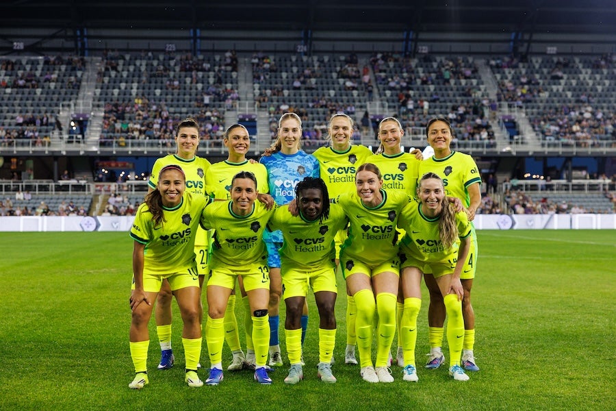 Photo of a soccer team posing in a stadium under bright lights
