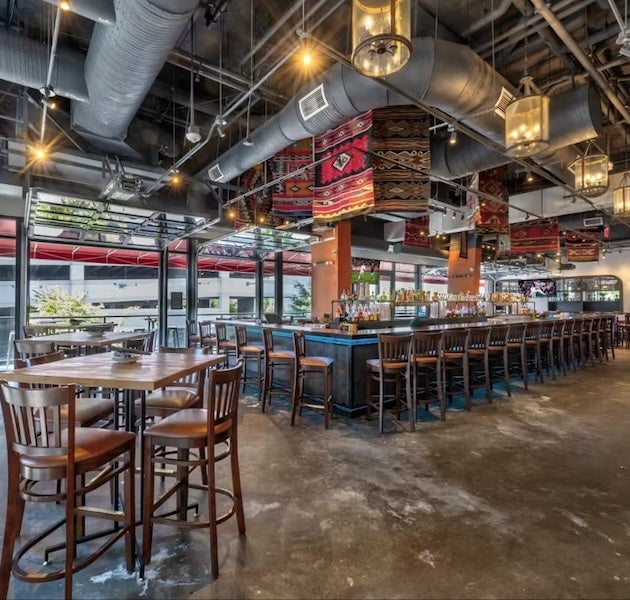 Empty bar with long counter, wooden chairs and blankets hanging from the ceiling