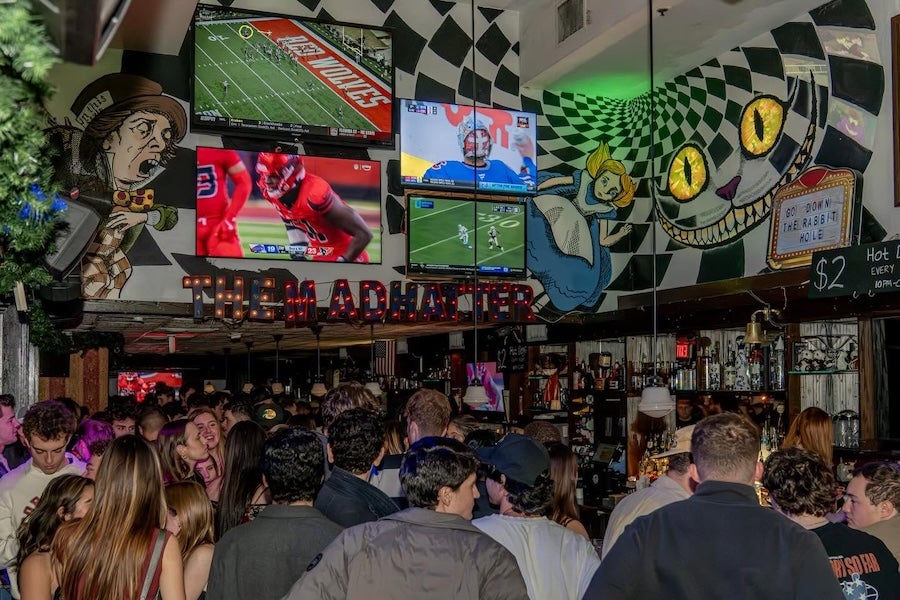 Crowded sports bar with TVs and colorful banners, patrons watching a game