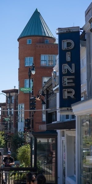 Street view with brick building and large diner sign, outdoor seating and light traffic