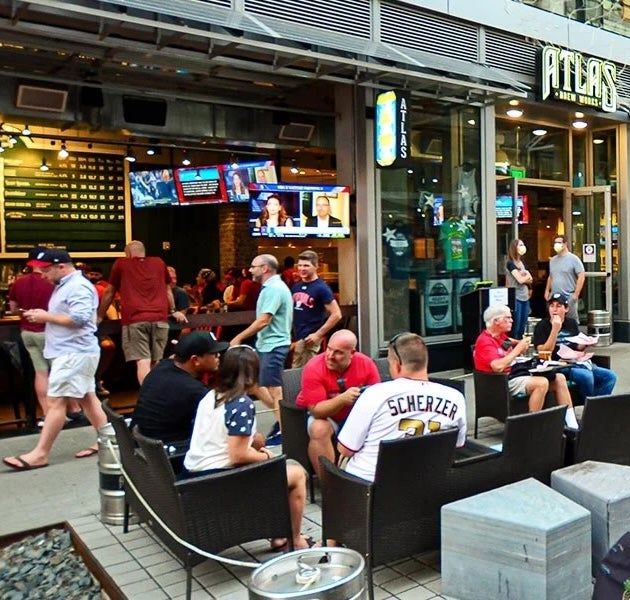 People sitting on outdoor patio at a busy bar and restaurant on a city street