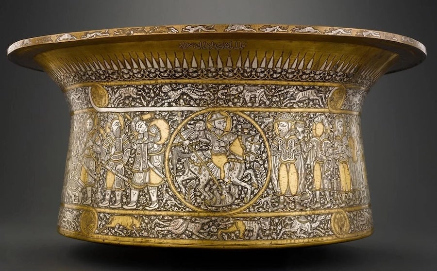 Gold and silver ornate islamic ceremonial bowl with engraved figures on dark background