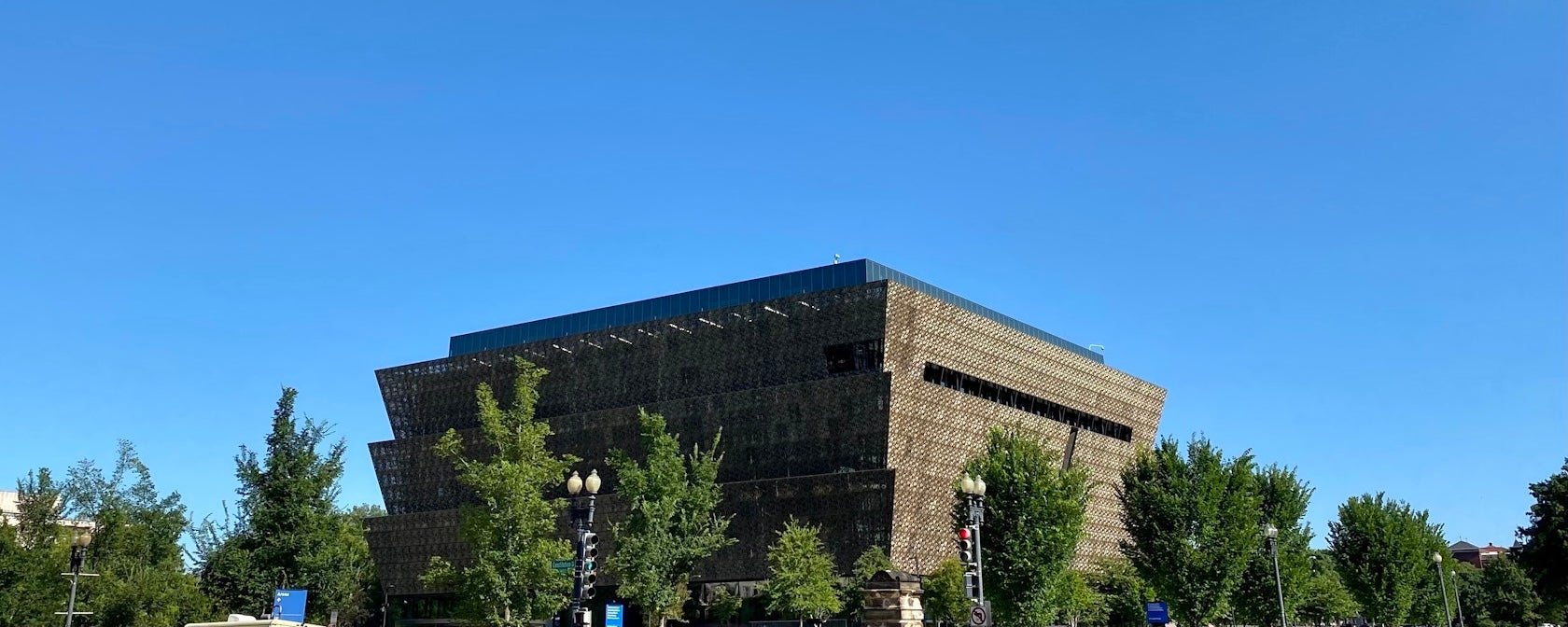 Modern dark building behind trees under clear blue sky